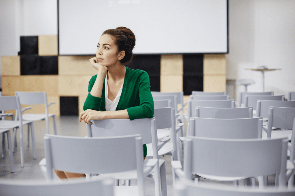 Young female teacher sitting in a classroom thinking alone.