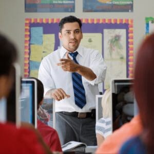 Male teacher standing confidently in front of a class while teaching.