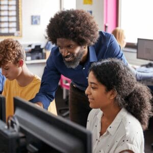 Teacher with a disability helping students work in computers.