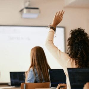 A classroom with students raising their hands.