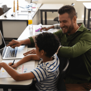 A man and a boy, both engaged in understanding the Education Support Class and Salary Structures in Victorian Government Schools, are diligently working on a laptop in a classroom.