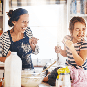 A mother and daughter, both students, are making cookies in the kitchen.